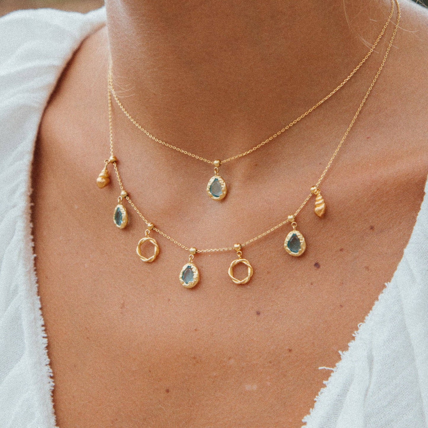 “Breloque Lysia en plaqué or avec pierre en verre turquoise, inspirée par la mer, fabriquée de manière éthique en France, Agapée.”